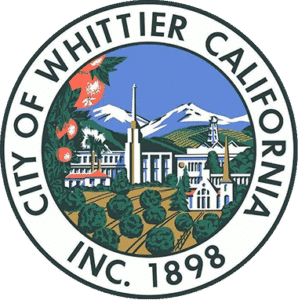 City of Whittier, California seal featuring citrus trees, buildings, and mountains.